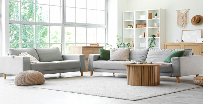 A living room with two couches and a large window in the background that is letting through natural light.